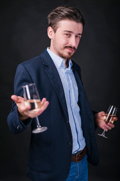 Jeune homme en bleu debout avec des verres de champagne dans les mains