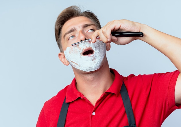 Jeune Homme Blond Confiant Barbier En Uniforme Visage Enduit De Mousse à Raser Rasage Rasoir Droit à Côté Isolé Sur Espace Blanc Avec Copie Espace