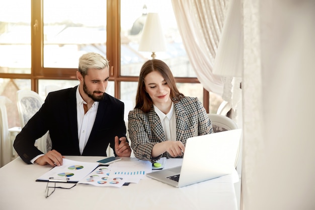 Photo gratuite jeune homme blond et femme brune regardent l'ordinateur et discutent des plans d'affaires