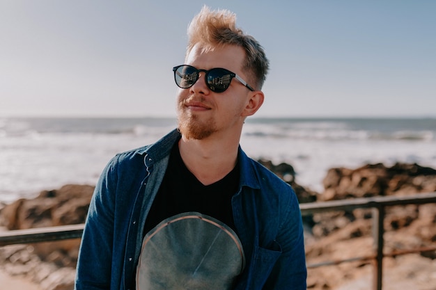 Photo gratuite jeune homme blond avec des lunettes de soleil sur la plage