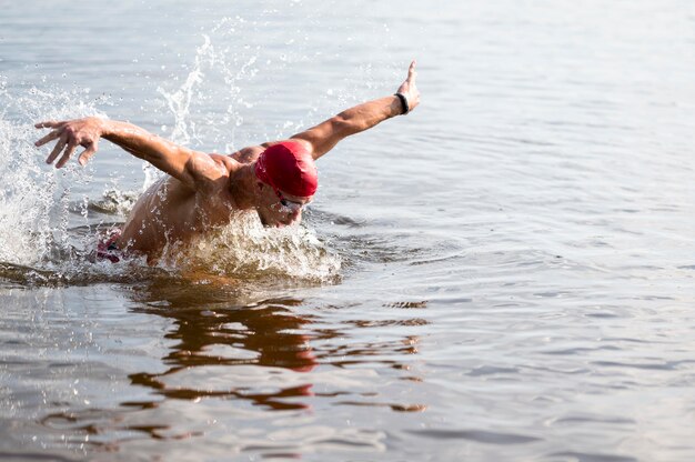 Jeune homme avec bonnet rouge nageant dans le lac