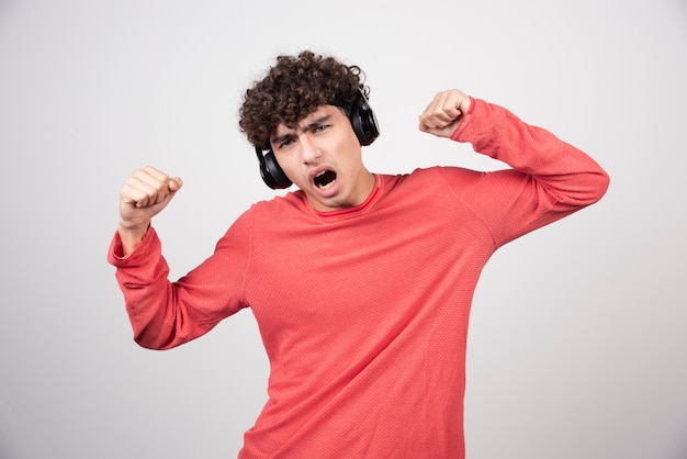 Jeune homme bouclé écoutant la chanson et chantant.