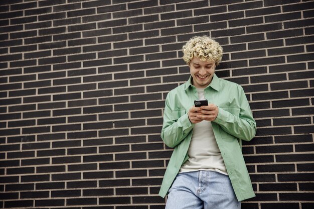 Jeune homme bouclé sourire au téléphone