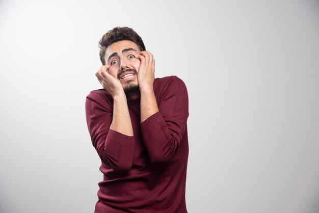 Un jeune homme brune debout et posant.