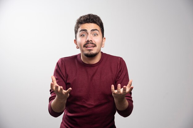 Un jeune homme brune debout et posant.