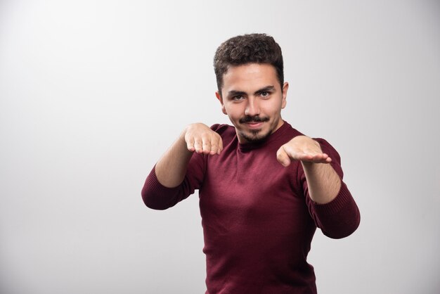 Un jeune homme brune debout et posant.