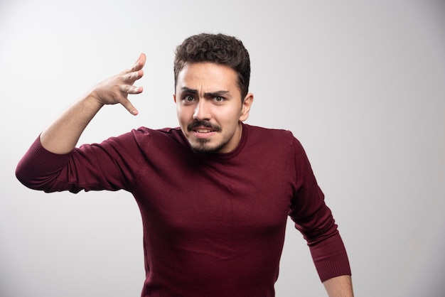 Un jeune homme brune debout et posant.