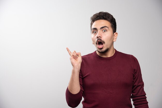 Un jeune homme brune debout et posant.