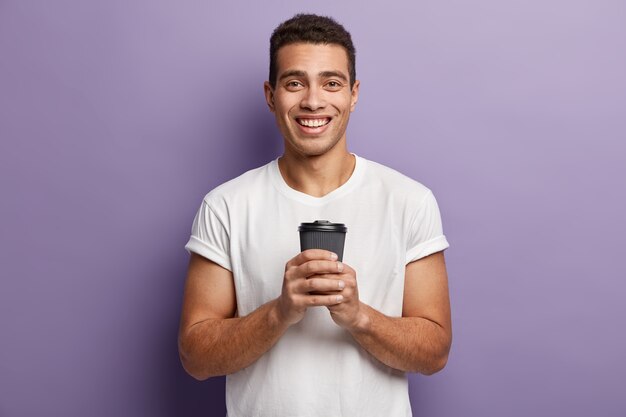 Jeune homme brunet portant un T-shirt blanc et tenant une tasse de café