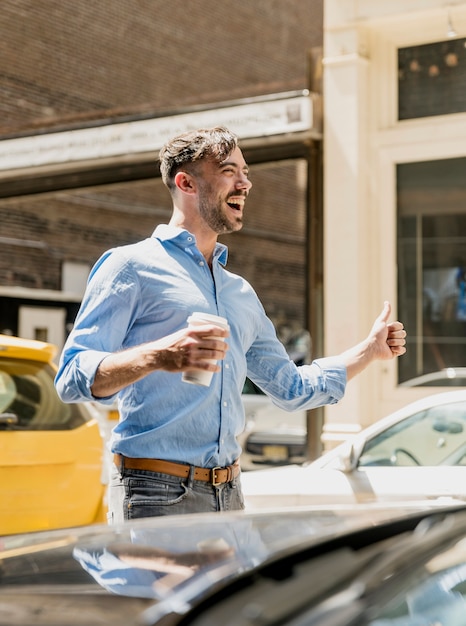 Jeune homme buvant du café et prendre un taxi