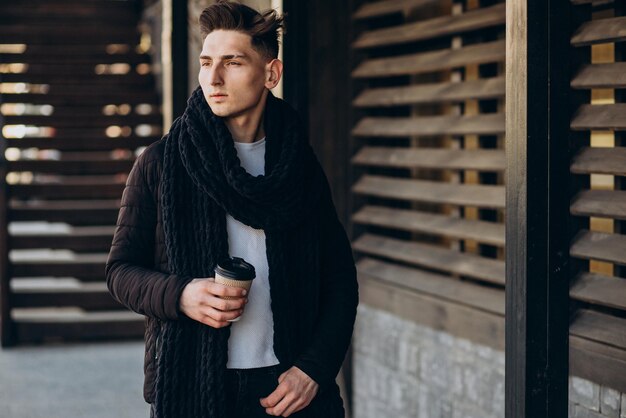 Jeune homme avec café marchant dans la rue