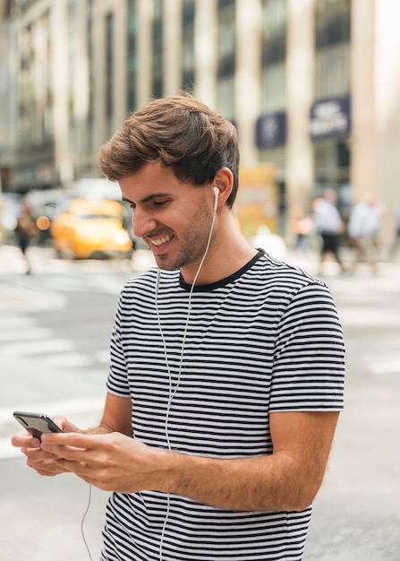 Jeune homme avec un casque en tapant sur un téléphone