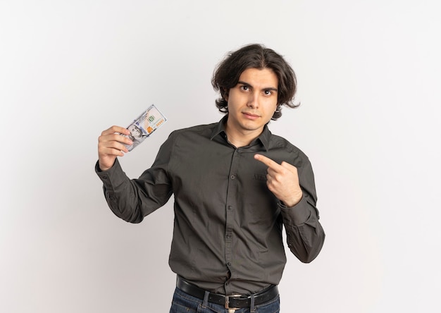Jeune homme caucasien beau confiant détient et points à l'argent isolé sur fond blanc avec espace de copie