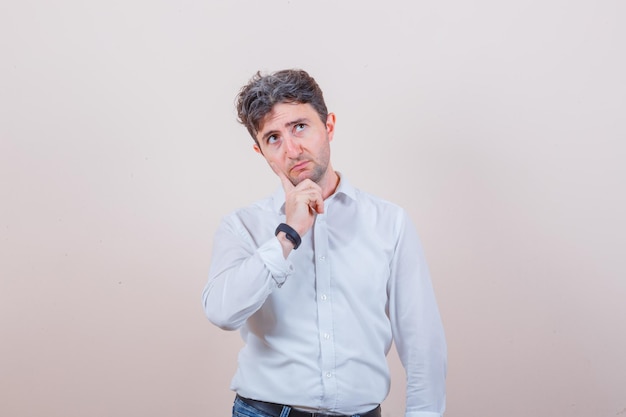 Jeune homme en chemise blanche, jeans et à la réflexion