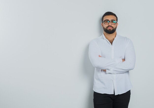 Jeune homme en chemise blanche, pantalon debout avec les bras croisés et à l'élégant