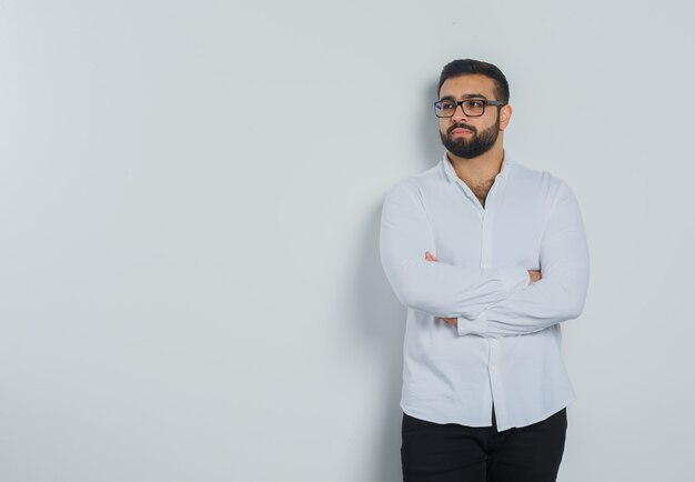 Jeune homme en chemise blanche, pantalon debout avec les bras croisés et à l'élégant