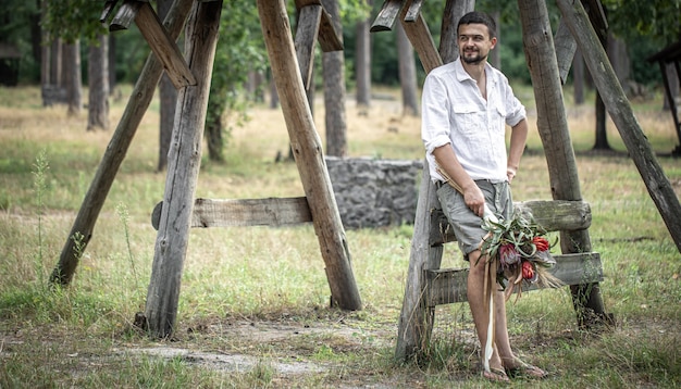 Jeune homme en chemise blanche tenant un bouquet de fleurs exotiques, concept de rencontres.