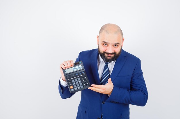 Jeune homme en chemise blanche, veste montrant une calculatrice et ayant l'air confiant, vue de face.