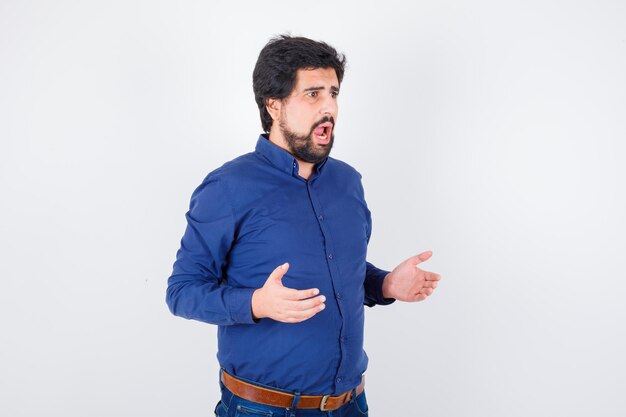 Jeune homme en chemise bleue à l'air anxieux , vue de face.