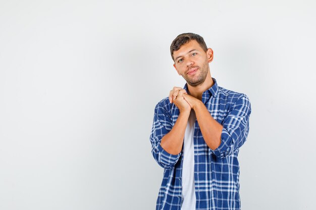 Jeune homme en chemise gardant les mains jointes et à la gentillesse, vue de face.