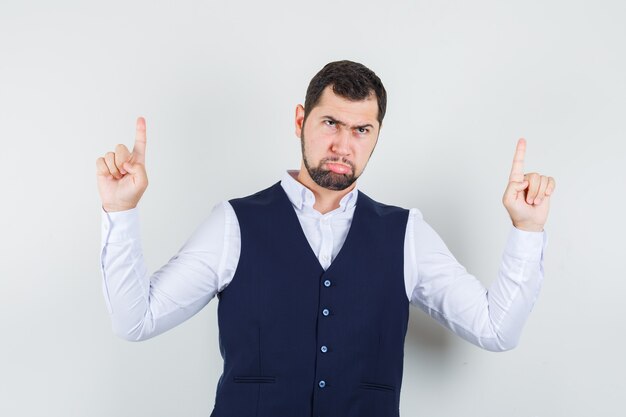 Jeune homme en chemise, gilet pointant vers le haut et à la sérieuse