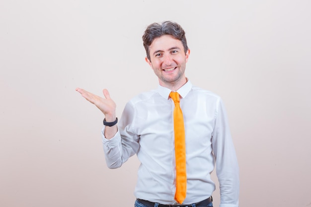 Jeune homme en chemise, jeans écartant la paume de la main et regardant joyeux