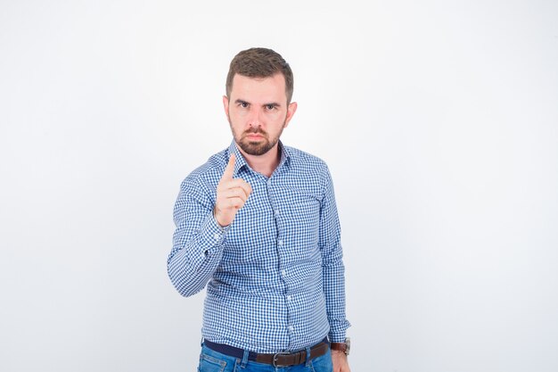 Jeune homme en chemise menaçant avec le doigt et à la grave, vue de face.