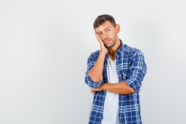 Jeune homme en chemise penchée joue sur la paume surélevée et à la vue fatiguée, de face.