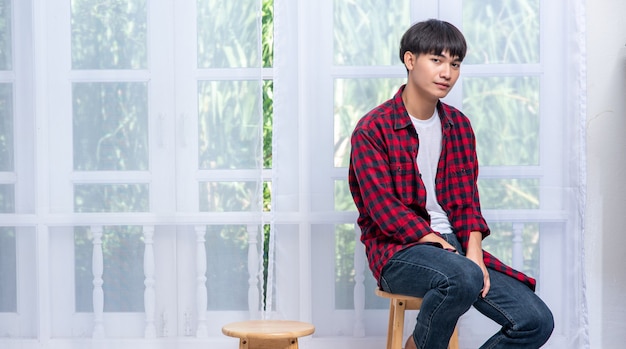 Un jeune homme en chemise rayée est assis sur une chaise haute.