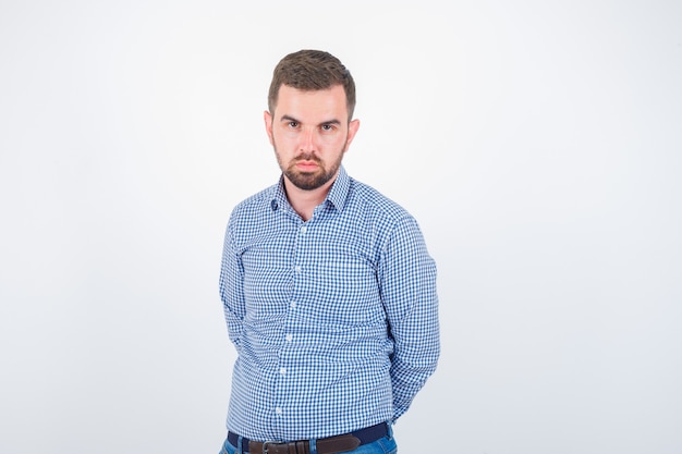 Jeune homme en chemise regardant la caméra et regardant sérieusement, vue de face.