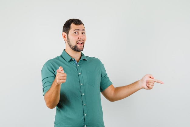 Jeune homme en chemise verte pointant de côté et ayant l'air confus, vue de face.