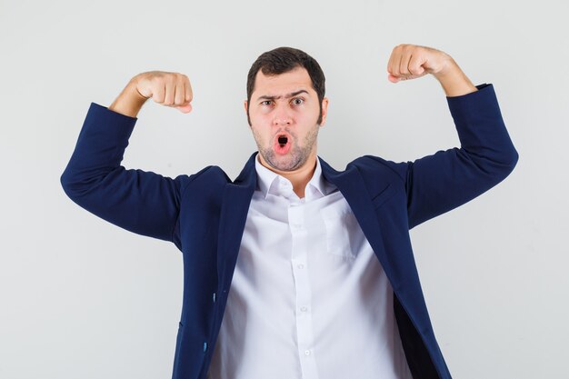 Jeune homme en chemise, veste montrant les muscles des bras et à la méchanceté