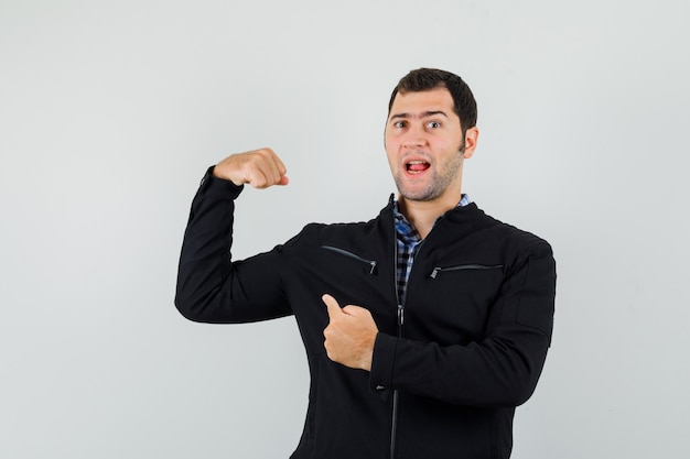 Jeune homme en chemise, veste pointant sur les muscles du bras et à la confiance