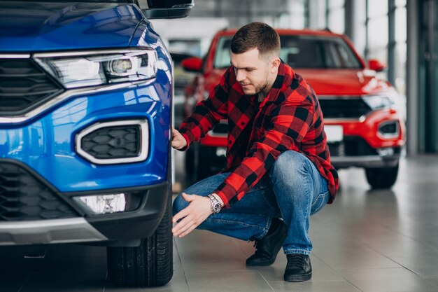 Jeune homme, choisir une voiture dans une salle d'exposition de voitures