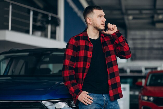 Jeune homme, choisir une voiture dans une salle d'exposition de voitures