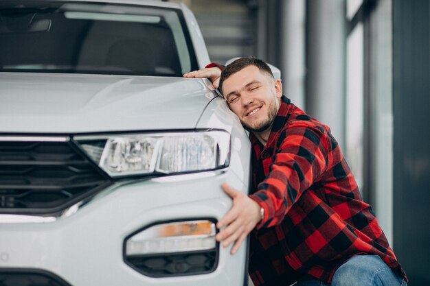 Jeune homme, choisir une voiture dans une salle d'exposition de voitures