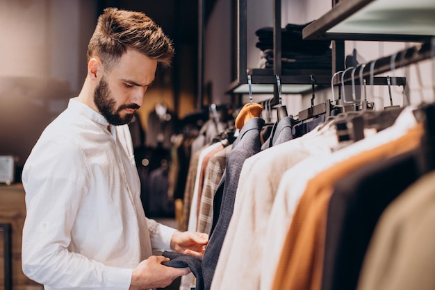 Jeune homme choisissant des chiffons dans une boutique de vêtements pour hommes