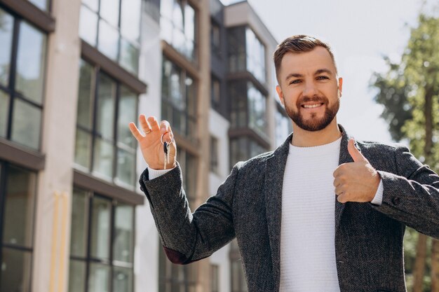 Jeune homme avec des clés vient d'acheter un nouvel appartement