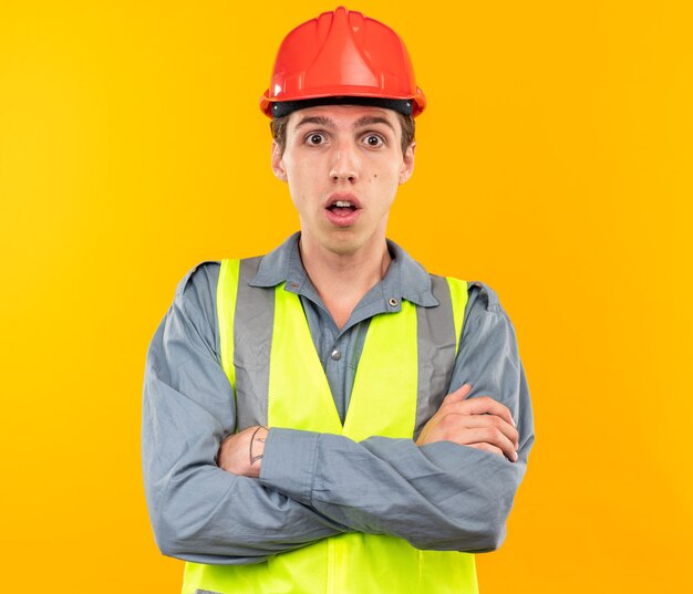 Jeune homme de constructeur surpris en uniforme croisant les mains