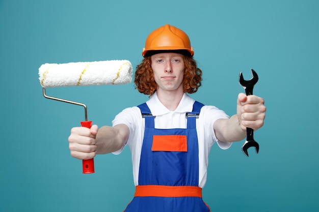 Jeune homme constructeur en uniforme isolé sur fond bleu