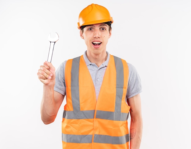 Jeune homme de construction impressionné en uniforme tenant une clé à fourche