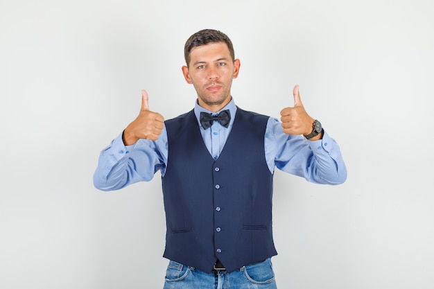 Jeune homme en costume, jeans montrant les pouces vers le haut et à la satisfaction