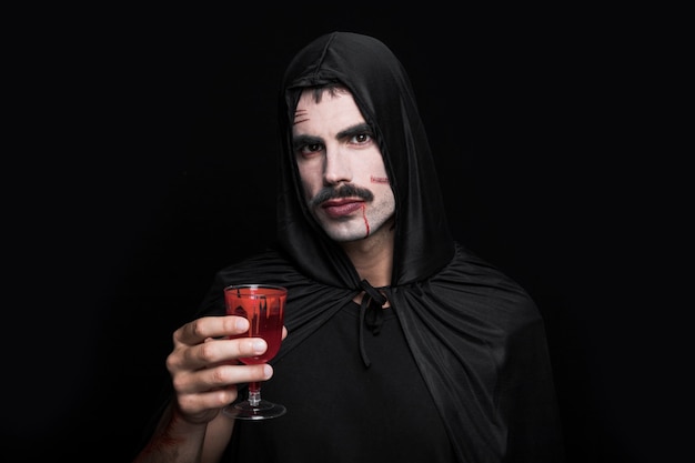 Jeune homme en costume noir qui pose en studio avec du verre