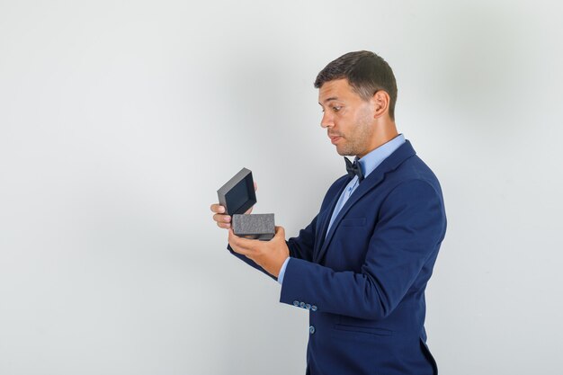 Jeune homme en costume ouvrant la boîte de montre et à la surprise.