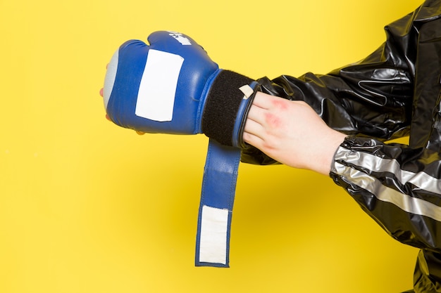 Jeune homme en costume de sport noir et gants de boxe bleus