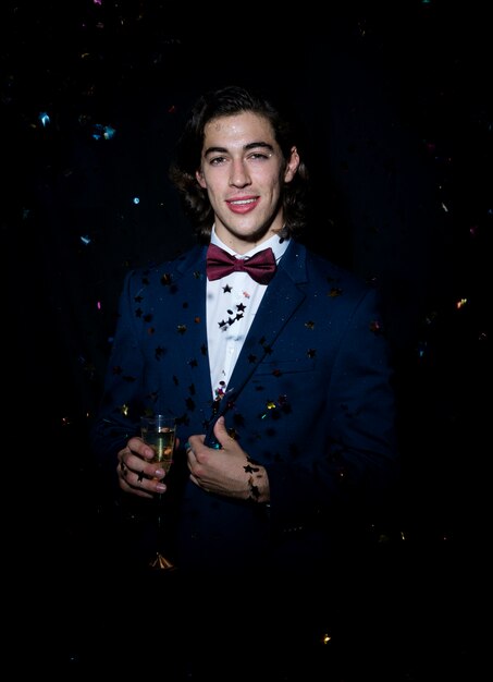 Jeune homme avec une coupe de champagne sous les paillettes