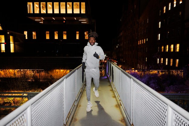Jeune homme courant sur un pont la nuit dans la ville