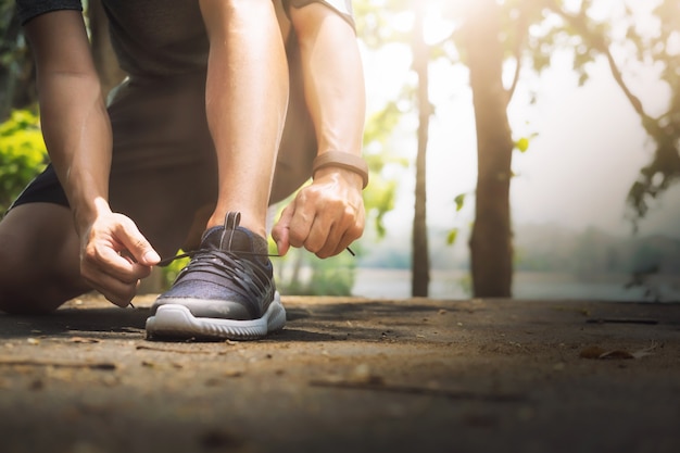 Jeune homme coureur attachant des lacets.