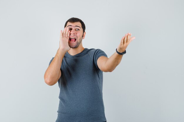 Jeune homme criant à quelqu'un en vue de face de t-shirt gris.