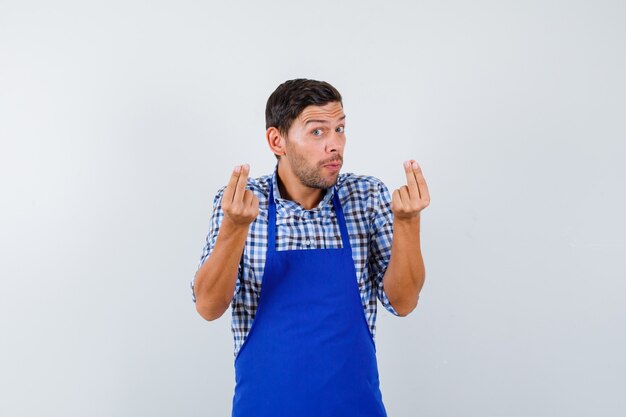 Jeune homme cuisinier dans un tablier bleu et une chemise